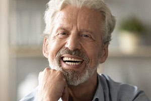 An older man smiling in the middle of a conversation