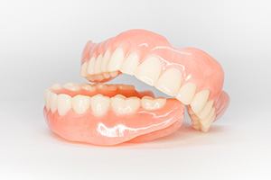 Upper arch of dentures leaning on lower arch with white background