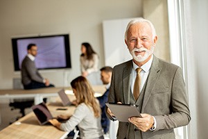 A senior business man working on a digital tablet in the office