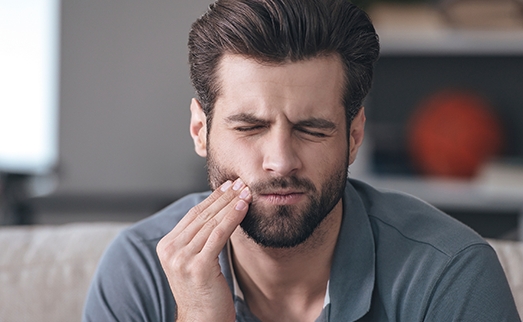 Man holding cheek in pain