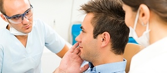 Man in dental chair holding cheek