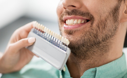 Man's smile compared with tooth color chart