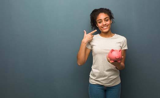 woman holding a piggy bank and pointing to her smile